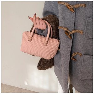 Close-up of pink tote bag with textured diamond pattern and round top handle