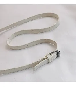 Détail d'une bandoulière en cuir blanc réglable avec boucle argentée et coutures fines