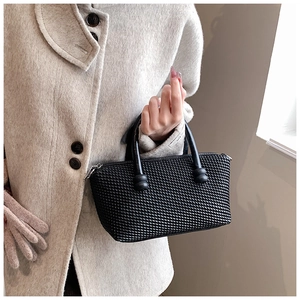 Detail shot of a black woven tote bag featuring a sturdy handle and premium textured finish