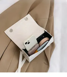 Détails intérieurs du mini sac blanc façon croco montrant sa capacité et ses doubles clips