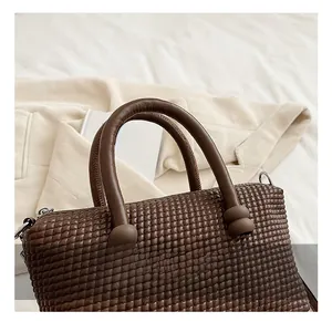 Detail of dark brown woven texture handbag with thick handles and ball ornaments