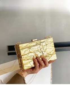 Detail of elegant gold evening bag with metallic pleat texture and delicate chain strap