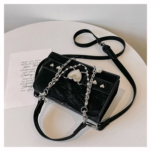 Détail du sac bandoulière noir brillant à plis avec boucle cœur et chaîne en métal argenté