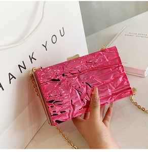 Detail of rose red crinkled texture evening bag with elegant gold chain and metal clasp
