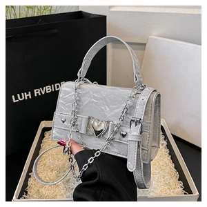 Détail du mini sac argenté texturé avec boucle coeur en métal et bandoulière chaîne