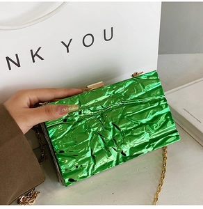 Close-up of vibrant lime green metallic clutch with gold chain and crinkled texture