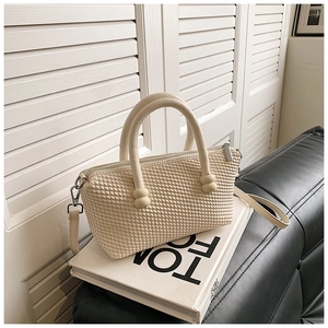 Detail showing cream woven texture and rounded handle of stylish women's tote bag