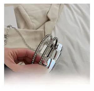 Close-up of sparkling rhinestone-encrusted round handles on a silver mini acrylic box bag