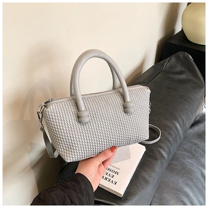 Detail of light grey woven texture tote bag held by model with cylindrical handles