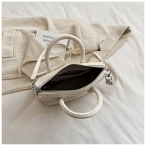 Close-up of cream woven tote bag with silver hardware on elegant background