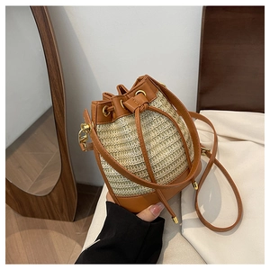 Handheld summer straw bucket bag with brown leather trim and drawstring closure