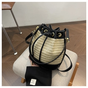Chic two-tone straw bucket bag with black leather trim and adjustable drawstring strap