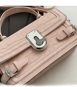 Close-up of pink crocodile texture leather surface with silver metal turn-lock closure