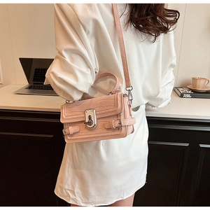 Pink crocodile pattern leather handbag with metal twist lock shown in a lifestyle setting