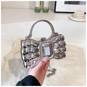 Close-up of a silver bow-shaped acrylic evening bag with a crystal-embellished mirror panel