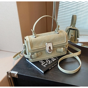 Detail view of sage green faux crocodile leather handbag with silver twist lock and strap