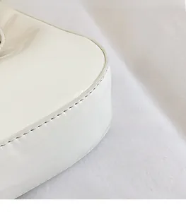 Detailopname van fijn stiksel en glanzend wit lakleer op de moderne handtas voor dames