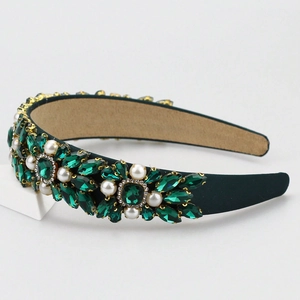 Detail of baroque headband with emerald crystals and pearls on dark green velvet base