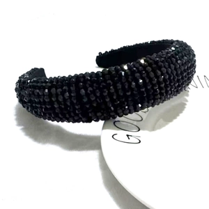 Close-up of black beaded wide headband with padded design on a ceramic plate