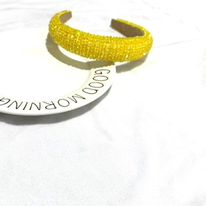 Macro detail of yellow beaded headband with sparkling sequins on a white ceramic plate