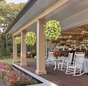 Three yellow artificial flower balls with metal chains hanging on porch pillars