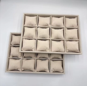 Macro view of two 12-slot beige velvet watch display trays with removable soft pillows