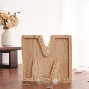 Detalle de hucha de madera en forma de M con panel acrílico y grano de madera natural