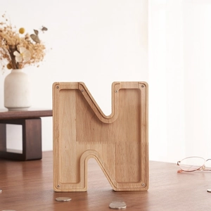 Detalle de hucha de madera en forma de N con panel acrílico transparente sobre la mesa