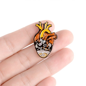 Macro detail of surreal anatomical heart enamel pin featuring celestial starry night art