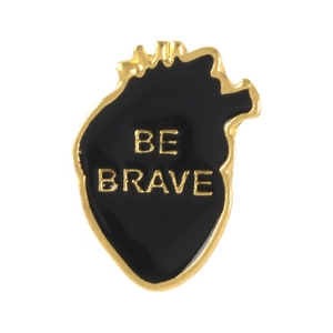 Detail of anatomical heart enamel pin in black and gold with Be Brave engraving