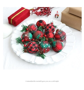 Detail of red and green plaid Christmas balls with pine needles and berries in a tray