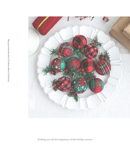 Close-up of vintage plaid Christmas ornaments with pine needles and berries in a ceramic dish
