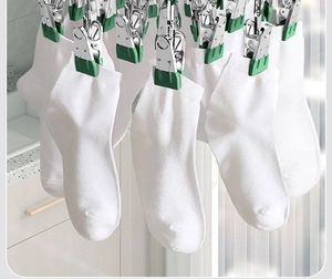 Close-up of durable stainless steel laundry hanger clips drying white socks on a balcony.