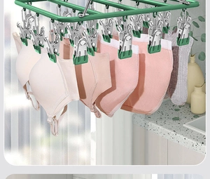 Close-up of a green stainless steel laundry drying rack with multiple functional clips holding clothes