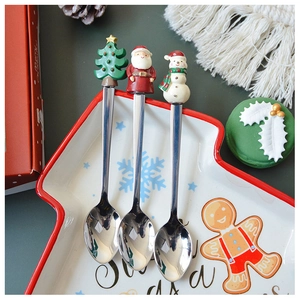 Detailed view of three stainless steel Christmas spoons in a tree-shaped ceramic dish