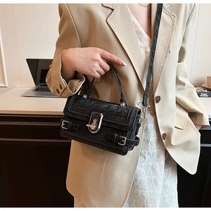 Close-up of black crocodile-embossed leather handbag with silver metallic twist lock