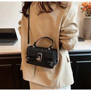 Close-up of black crocodile-embossed leather handbag with silver rotary metal lock