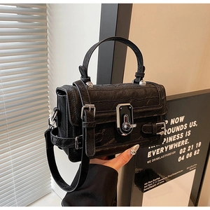 Detailed view of black crocodile pattern leather handbag with silver square twist lock