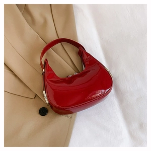 Detail van de rode lakleren hobo-tas met glanzende textuur op beige en wit textiel