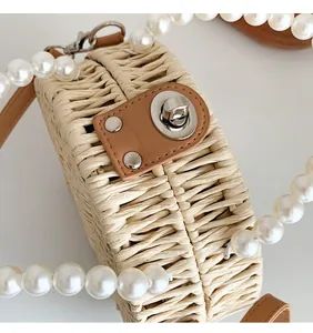 Close-up of woven straw bag featuring pearl handle and silver twist lock detail
