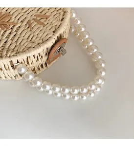 Detailed macro view of retro woven straw bag featuring white pearl strap and leather buckle