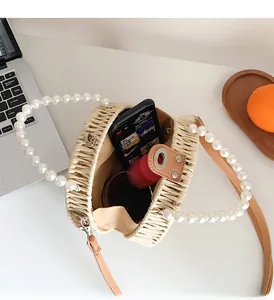 Detail of round straw crossbody bag with pearl handle showing spacious inner lining