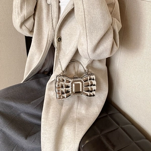 Silver metallic bow-shaped handbag with wave texture and chain strap worn by a model