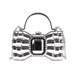 Silver bow-shaped acrylic clutch bag with a mirrored finish and metallic chain strap