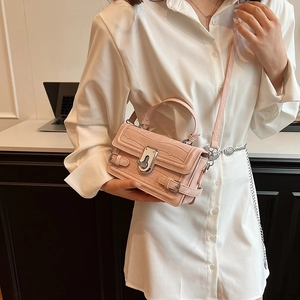 Pink croc-embossed crossbody bag with silver hardware and adjustable strap on a model