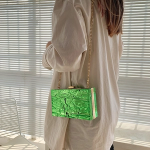Chic emerald green quilted crossbody bag with gold chain strap in sunlight