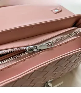 Close-up of pink woven leather shoulder bag showing smooth silver metal zipper detail