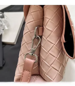 Detailed macro view of pink woven leather texture and silver metal hook clasp on a bag