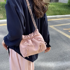 Borsa a secchiello plissettata rosa con fiocchi e tracolla a catena sulla modella