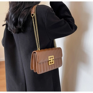 Detail of brown quilted leather crossbody bag with gold chain strap and metal clasp